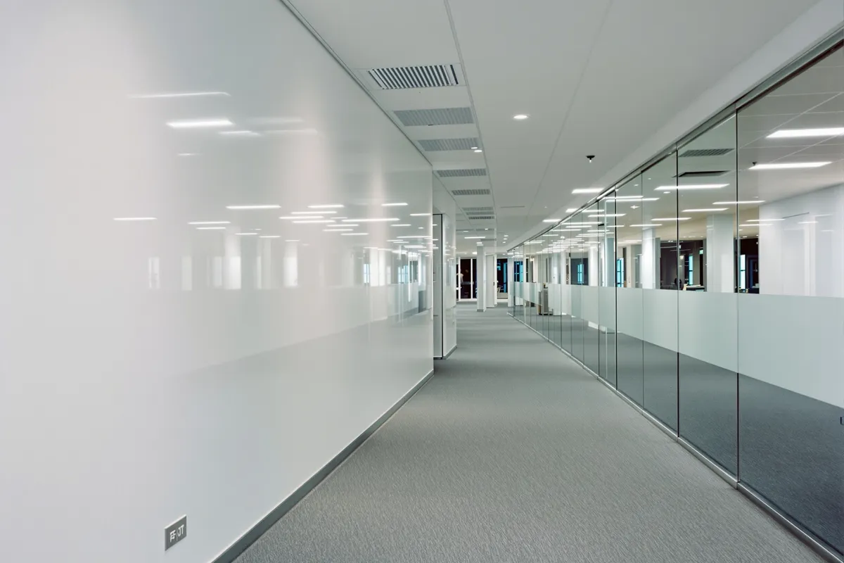 A quiet office corridor with glass-walled meeting rooms